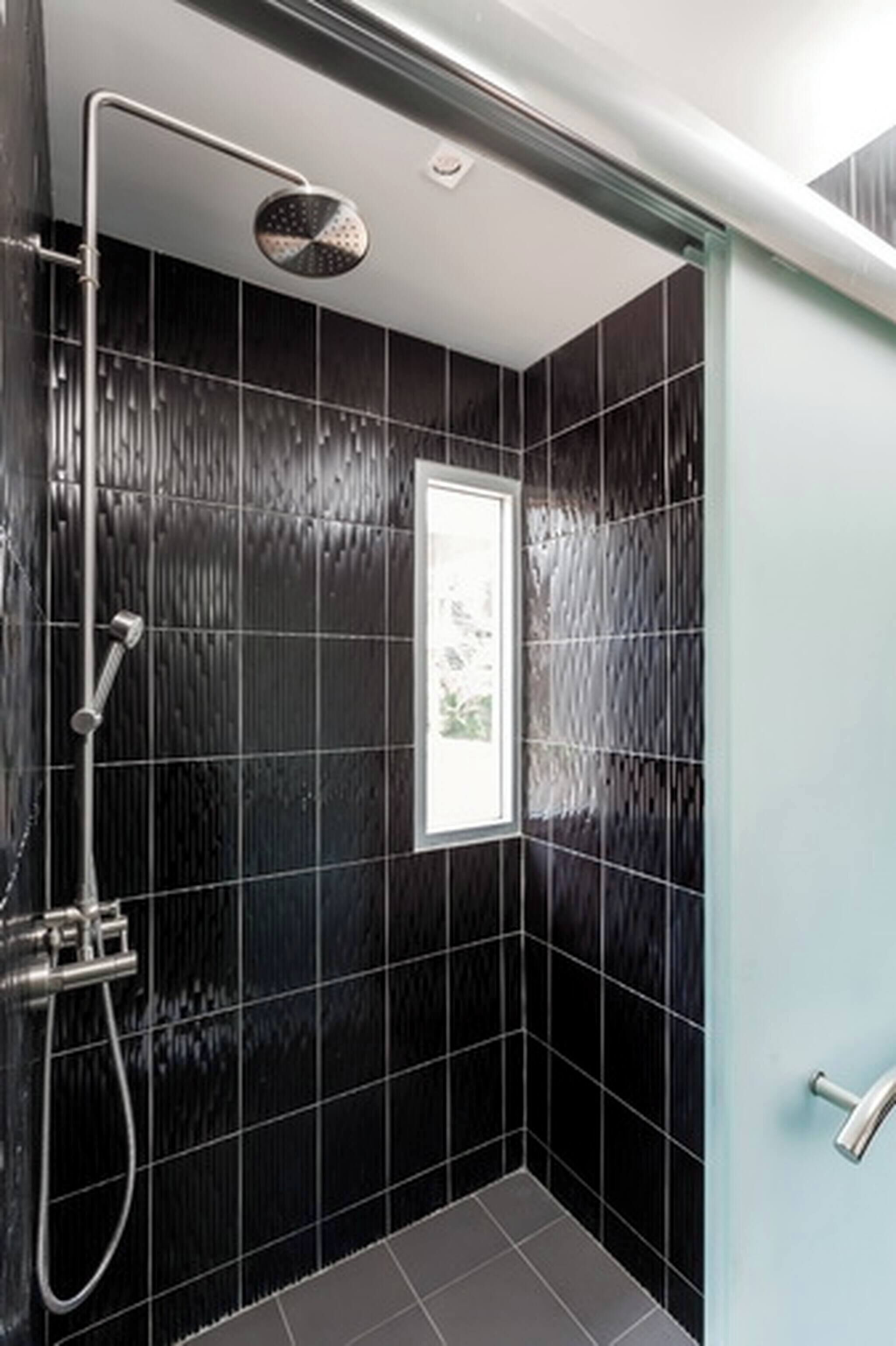 A modern shower with a handheld showerhead and a wall-mounted faucet.