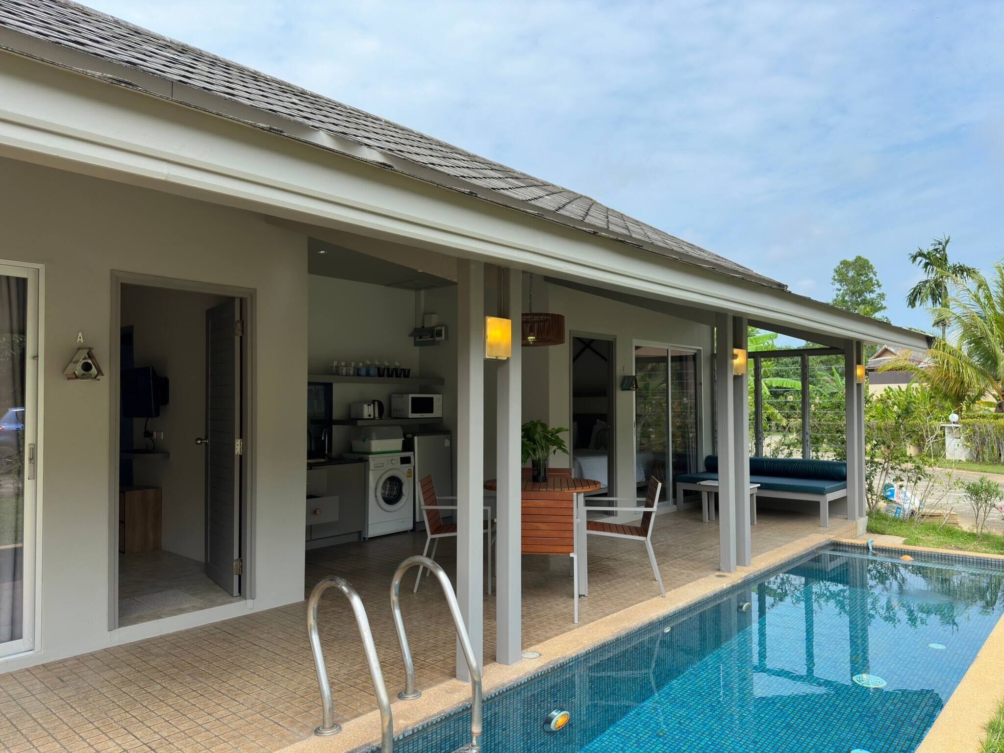Uma área de piscina ao ar livre coberta, com cozinha e espaço para sentar.