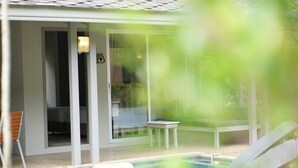 A pool area with a lounge chair, a small table, and a bench. - 2 Bedroom Neer Phuket Airport (Sa Khu)