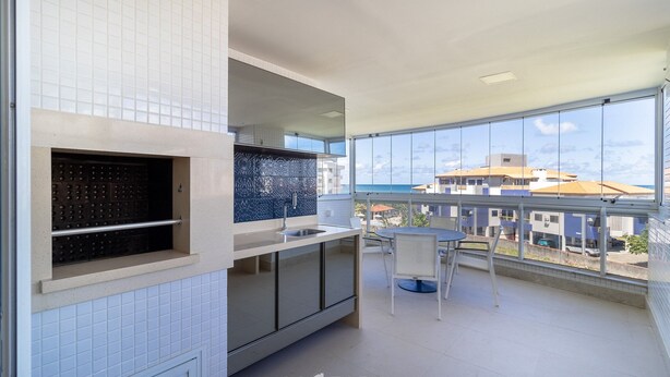 A modern kitchen with a large window, a dining area, and a view of buildings. - Apartment w/ Barbecue 160m From the Beach Rgl0304 (Florianópolis)