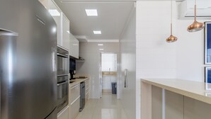 A modern kitchen with stainless steel appliances, a light-colored countertop, and pendant lighting. - Apartment w/ Barbecue 160m From the Beach Rgl0304 (Florianópolis)