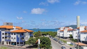 A residential area with multi-story buildings, a parking lot, and a view of the sea. - Apartment w/ Barbecue 160m From the Beach Rgl0304 (Florianópolis)
