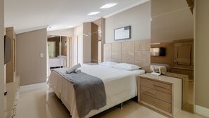 A modern hotel room with a large bed, a bedside table with a lamp, a wardrobe, and a flat-screen TV mounted on the wall. - Apartment w/ Barbecue 160m From the Beach Rgl0304 (Florianópolis)