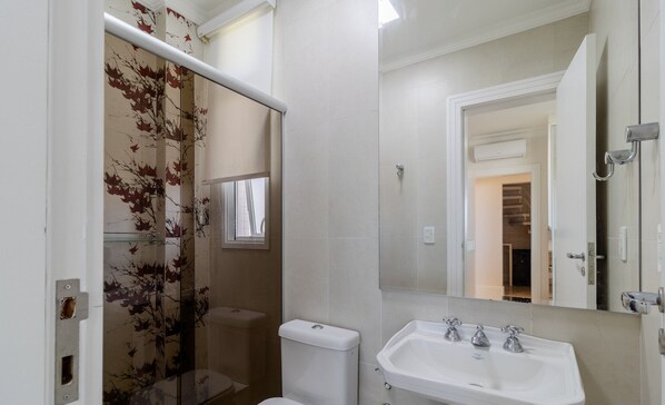 A bathroom with a toilet, a sink, and a glass shower enclosure with a leaf pattern. - Apartment w/ Barbecue 160m From the Beach Rgl0304 (Florianópolis)