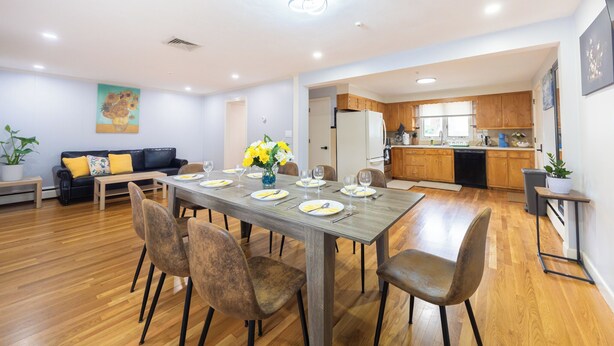 Un vaste espace de vie comprenant une table à manger pour six personnes, un canapé et une cuisine en arrière-plan.