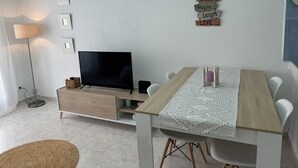Un salon moderne doté d’un téléviseur à écran plat, d’une table à manger en bois et d’un panneau mural affichant des citations inspirantes.