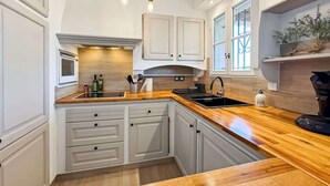 Une cuisine moderne avec des meubles blancs, un plan de travail en bois et un four encastré.
