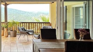 Un balcon avec une table, des chaises et des plantes en pot.