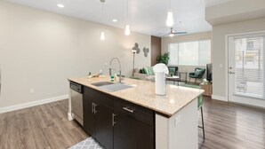 A modern kitchen with a central island, built-in dishwasher, and pendant lighting. - Cozy Green 1BR Retreat Pool, Hot Tub & Near ASU & Mill Ave (Tempe)
