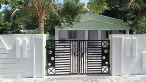 Un cancello con un muro bianco e un edificio con tetto verde sullo sfondo.