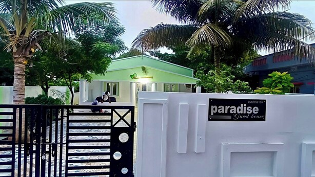 Un cancello con un cartello che riporta 'Paradise Guest House' e una palma sullo sfondo.
