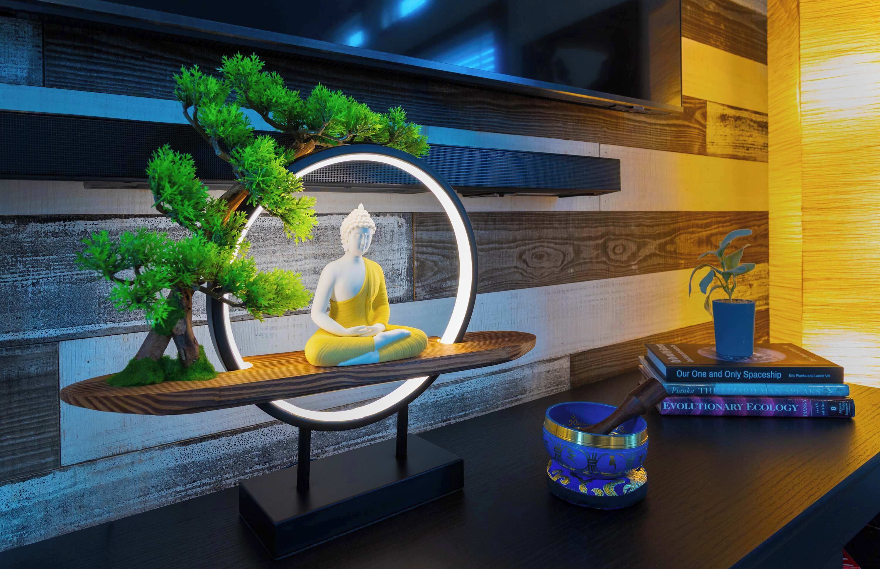 A meditation area with a statue, a small tree, and books on a table.