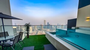 A balcony with a pool, green artificial grass, and a city view. - 2 Bed, Private Pool, Big Terrace, Solysian Stay (Dubai)