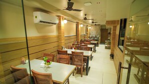 A restaurant with wooden panel walls, ceiling fans, and tables with chairs. - Hotel Amber Paramount (Mumbai)