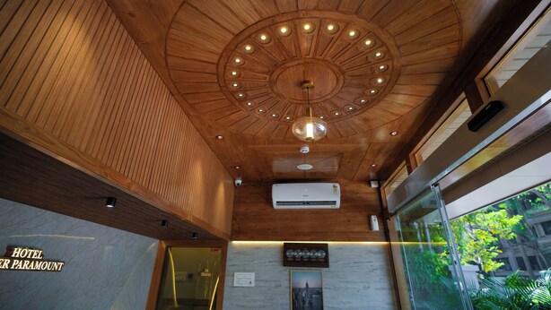 A hotel lobby with a wooden ceiling, a large glass window, and a sign reading "HOTEL PARAMOUNT". - Hotel Amber Paramount (Mumbai)