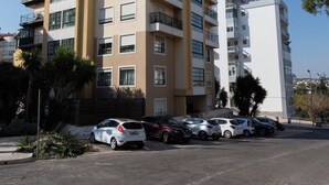 A multi-story residential building with balconies, a parking lot, and a clear blue sky. - Bright Studio with Balcony in Central Cascais (Cascais)