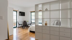 A bedroom with a bed, a desk, chairs, a wardrobe, and a TV. - Bright Studio with Balcony in Central Cascais (Cascais)