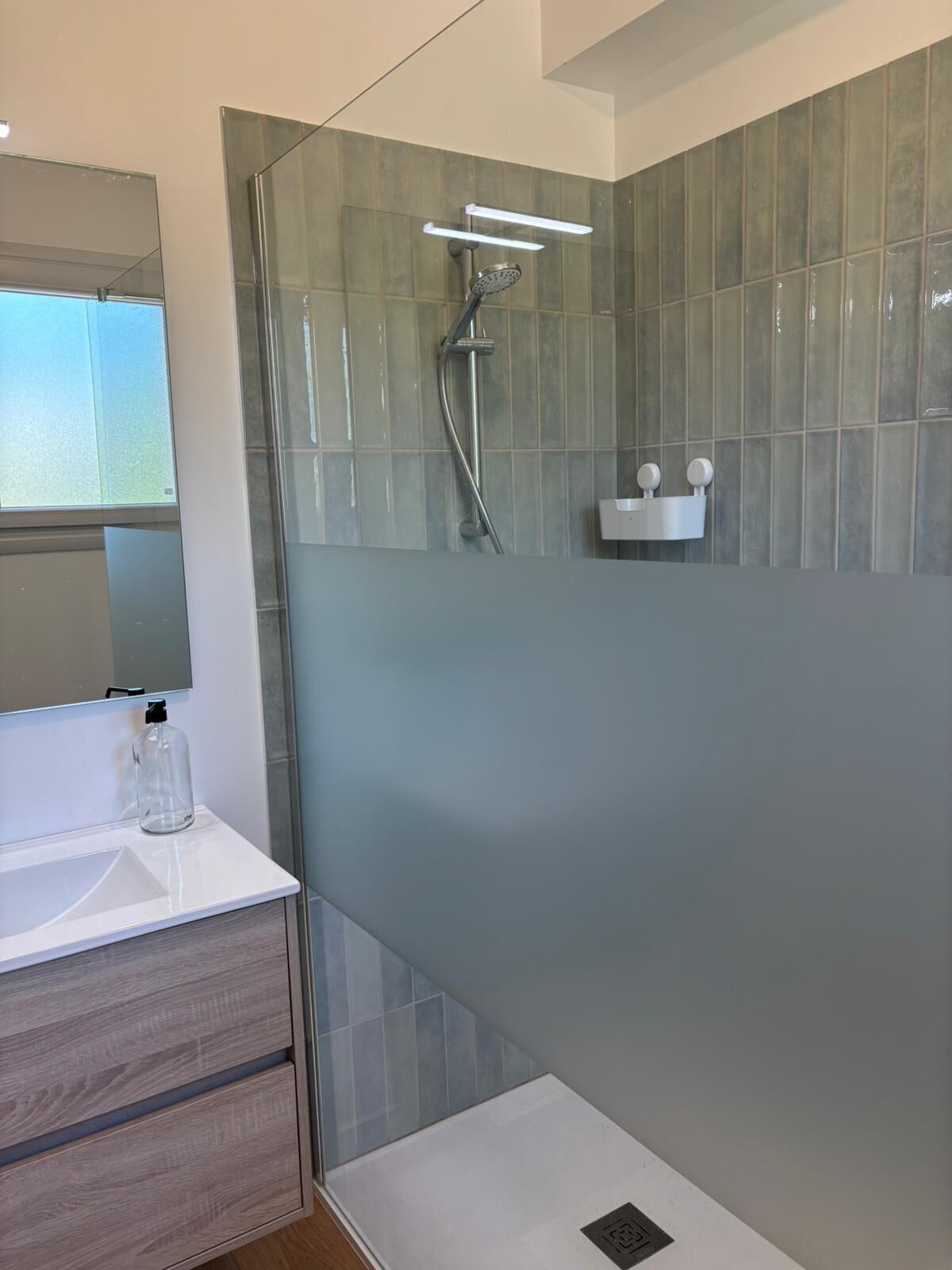 Un baño moderno con cabina de ducha de vidrio, un lavabo blanco y un espejo.