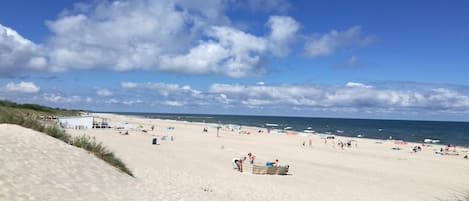 A beach with people, umbrellas, and a dune.