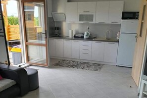 A compact kitchen with white cabinets, a built-in microwave, and a refrigerator.