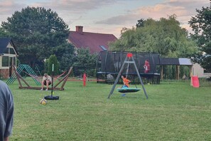A grassy outdoor area with swings, a trampoline, and a slide. - Holiday home, 3 bedrooms, fishing pond, sauna (Wodnica)