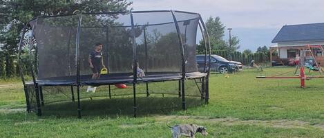 Un trampolín con red de seguridad en un área con césped.