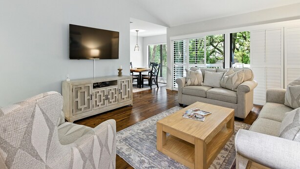 A modern living room with a flat-screen TV, a wooden coffee table, and a beige sofa. - Lighthouse Tennis Villas: Walk to both Harbor Town, Shops at Sea Pines STR077622 (Hilton Head)