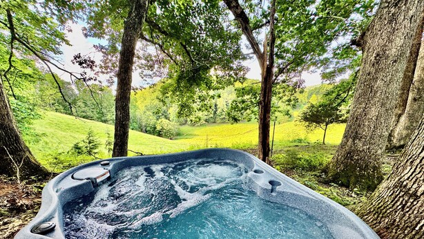 A hot tub in a forested area with a wooden deck.