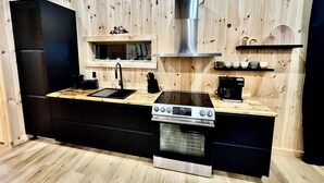 A compact kitchen with a built-in oven, a stovetop, and a window above the sink.