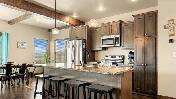 A modern kitchen with dark wood cabinets, stainless steel appliances, and a central island with bar stools. - Lakefront Sleeps 20 | Boat Slip Included | 5 Min to SDC (Branson)