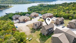 An aerial view of a residential area with multiple houses, a large body of water, and a bridge in the distance. - Lakefront Sleeps 20 | Boat Slip Included | 5 Min to SDC (Branson)