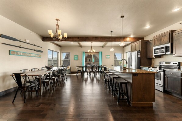 A spacious kitchen with a central island, wooden flooring, and modern appliances. - Lakefront Sleeps 20 | Boat Slip Included | 5 Min to SDC (Branson)