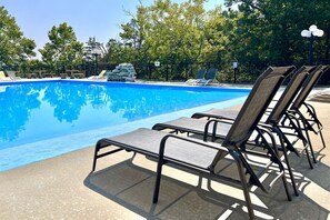 A swimming pool with lounge chairs and a stone stack.