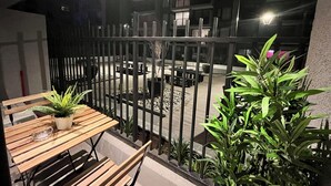 A balcony with a wooden table and chairs, surrounded by potted plants. - M&C DC 108 (Santiago)