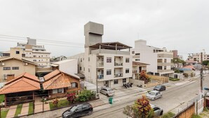 A residential area with multi-story buildings, a street with parked cars, and a visible power line. - Apt Close to the Beach in Canasvieiras Rfs205 (Florianópolis)