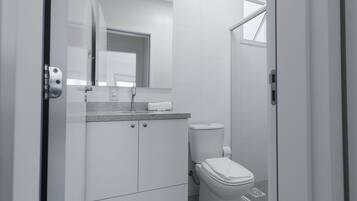 Un baño moderno con inodoro, lavamanos y espejo.