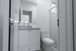 Un baño moderno con inodoro, lavamanos y espejo.