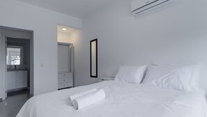 A modern hotel room with a neatly made bed, a bathroom with a mirror, and a white color scheme. - Apt w/ BBQ 300m From the Beach in Floripa Res201 (Florianópolis)