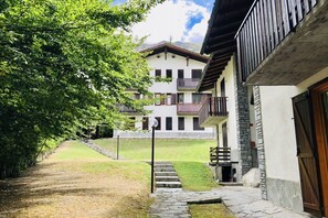 Un bâtiment doté de nombreux balcons, d’un chemin en pierre et d’une zone herbeuse.