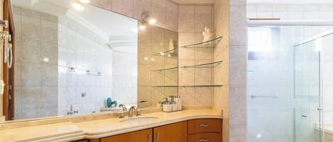 A modern bathroom with a large mirror, wooden cabinets, and a glass shower enclosure.