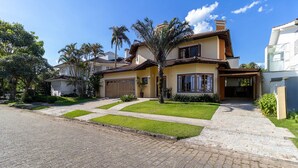 A residential house with a paved driveway, a well-maintained lawn, and a palm tree. - Duplex House w/ Pool, 850m From the Beach Rdt0124 (Florianópolis)