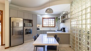 A modern kitchen with stainless steel appliances, a dining area with a table and chairs, and a window providing natural light. - Duplex House w/ Pool, 850m From the Beach Rdt0124 (Florianópolis)