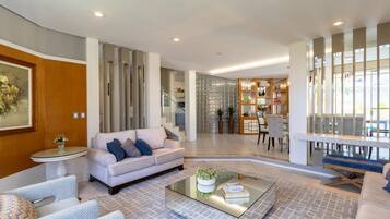 A modern living room with a sofa, armchairs, a coffee table, and a dining area with a table and chairs.