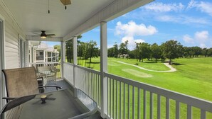 A covered porch with a table and chairs, overlooking a well-manicured golf course. - Waterway Village - 13H (Myrtle Beach)