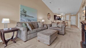 A spacious living room with two sofas and a coffee table, a dining area with a kitchen in the background, and a ceiling fan. - Waterway Village - 13H (Myrtle Beach)