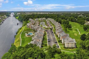 Zona residencial con un río, un puente y una hilera de casas adosadas con piscina y campo de golf.