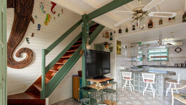 A kitchen with a bar area, a television, and a staircase with green railings. - Pleasant Townhouse w/ BBQ 90m From the Sea Rdd657 (Florianópolis)