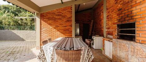 Un patio exterior con pared de ladrillo, una mesa cubierta con sillas y una lavadora.
