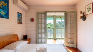 A bedroom with a bed, a nightstand, a wall-mounted heater, and a door leading outside. - Pleasant Townhouse w/ BBQ 90m From the Sea Rdd657 (Florianópolis)