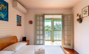 Une chambre à coucher comprenant un lit, une table de chevet, un radiateur fixé au mur et une porte donnant sur l’extérieur.
